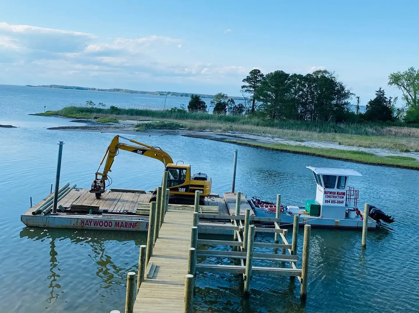 The barge, excavator and push boat tied up beside a new pier and boat lift