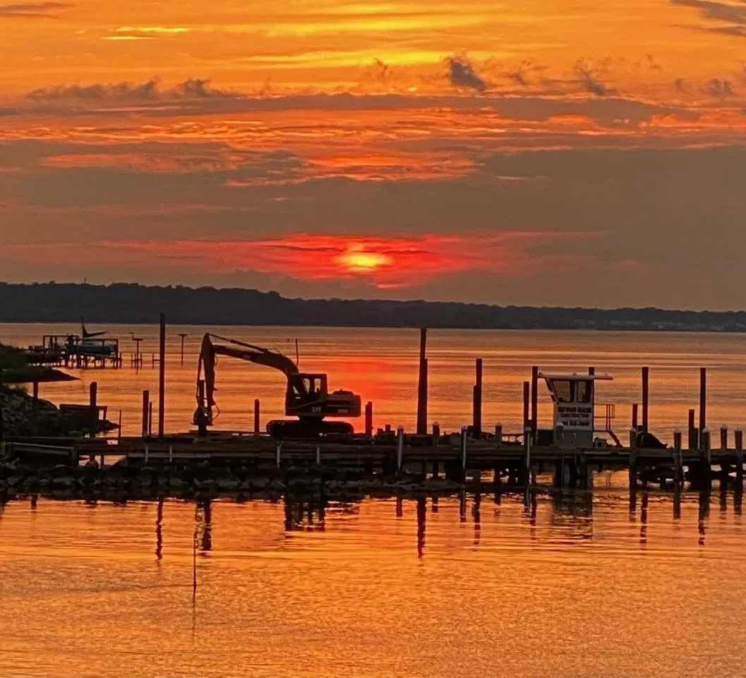 The Haywood Marine work barge silhouetted against a red sun setting over the water