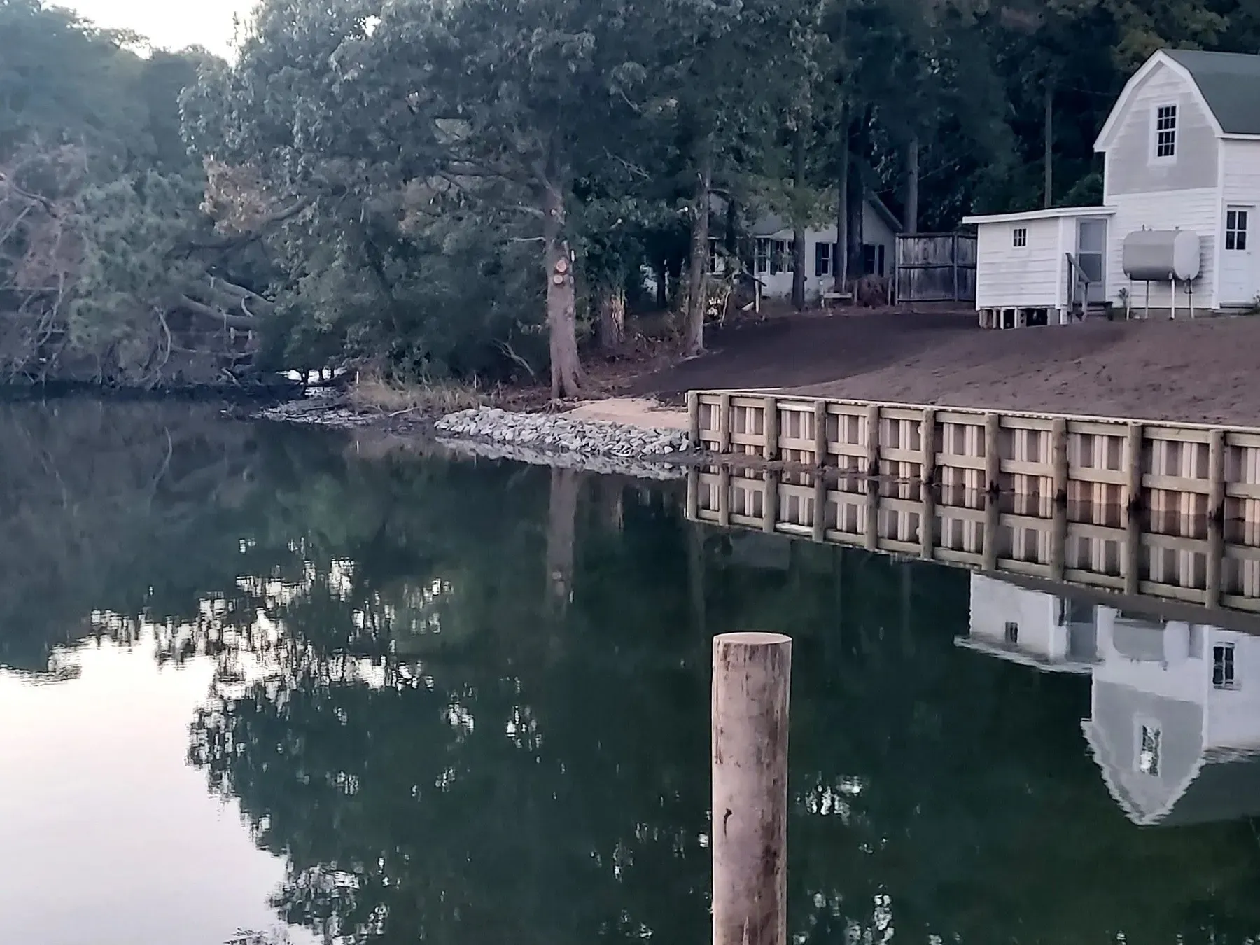 Bulkhead along a quiet cove in front of a white house
