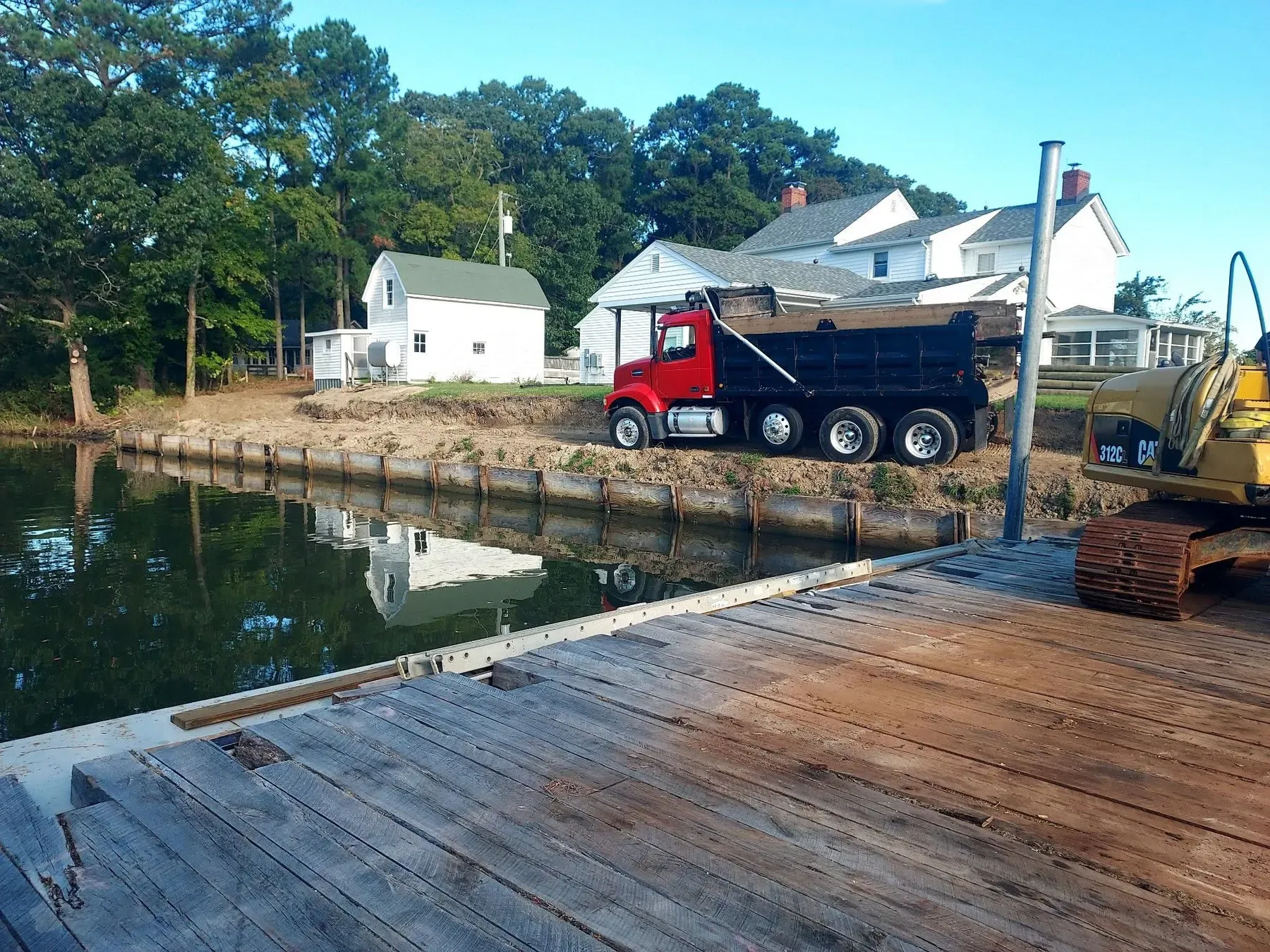 Dump truck delivering fill behind a new bulkhead