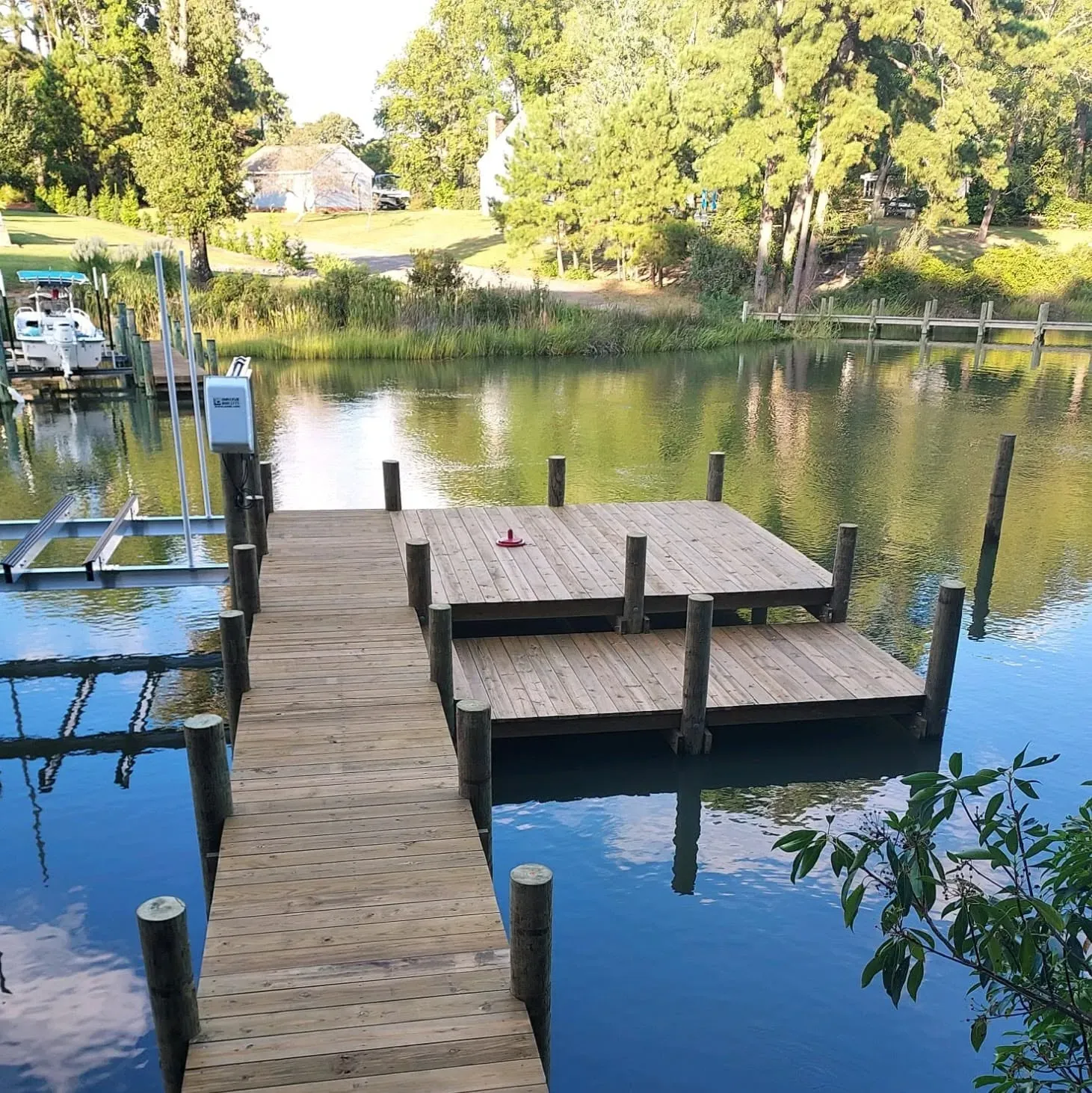 Dock with a square platform on a calm, tree-lined creek