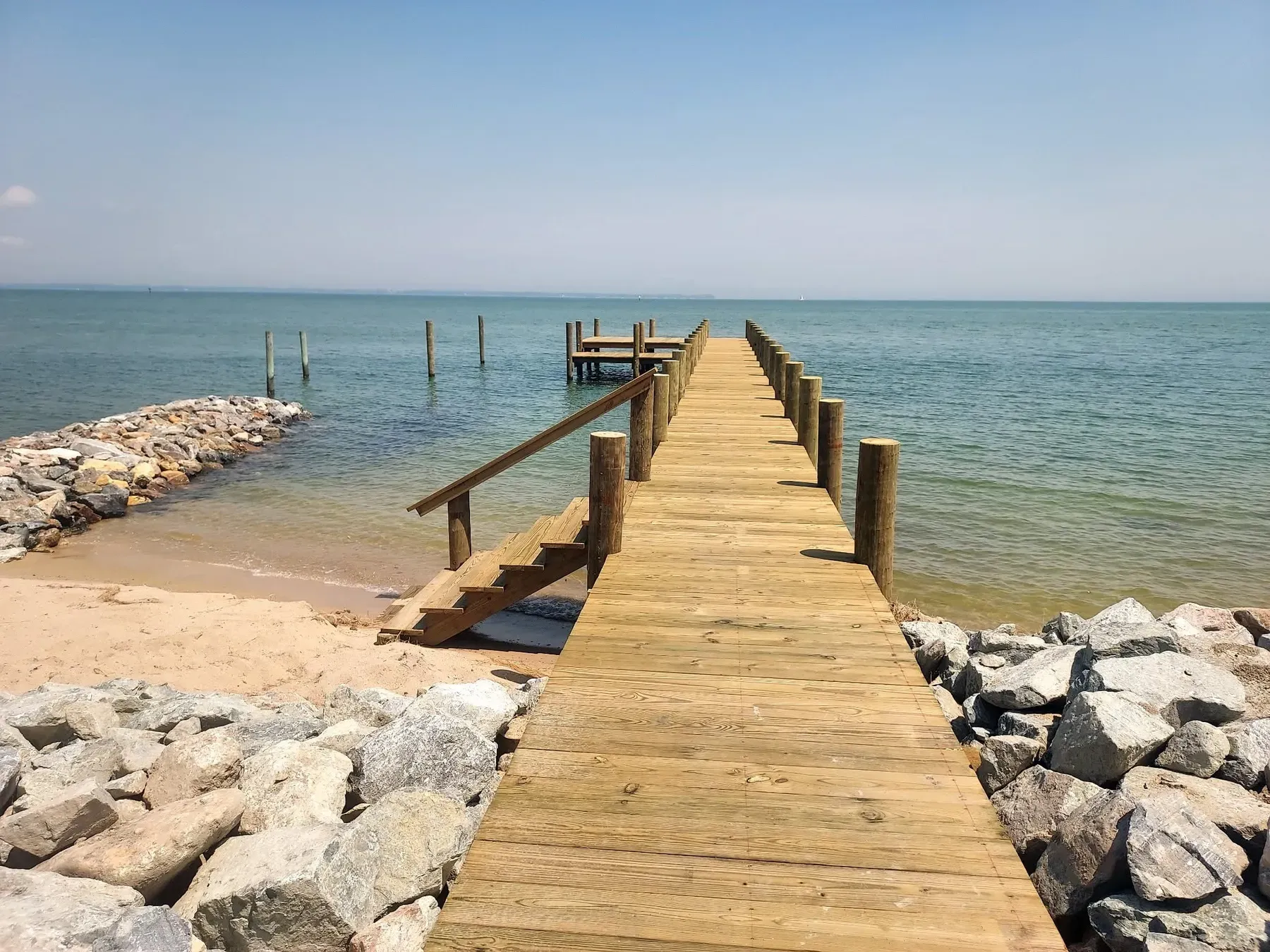 New pier with stairs down to a sandy beach and rock revetment