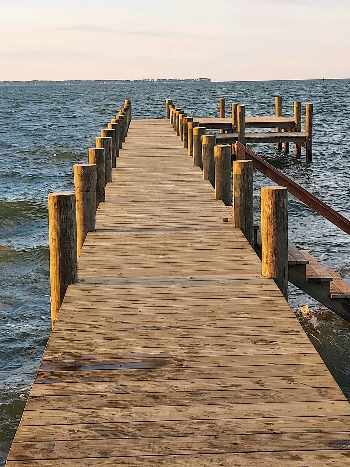 Long pier with a handrail stretching out over the bay